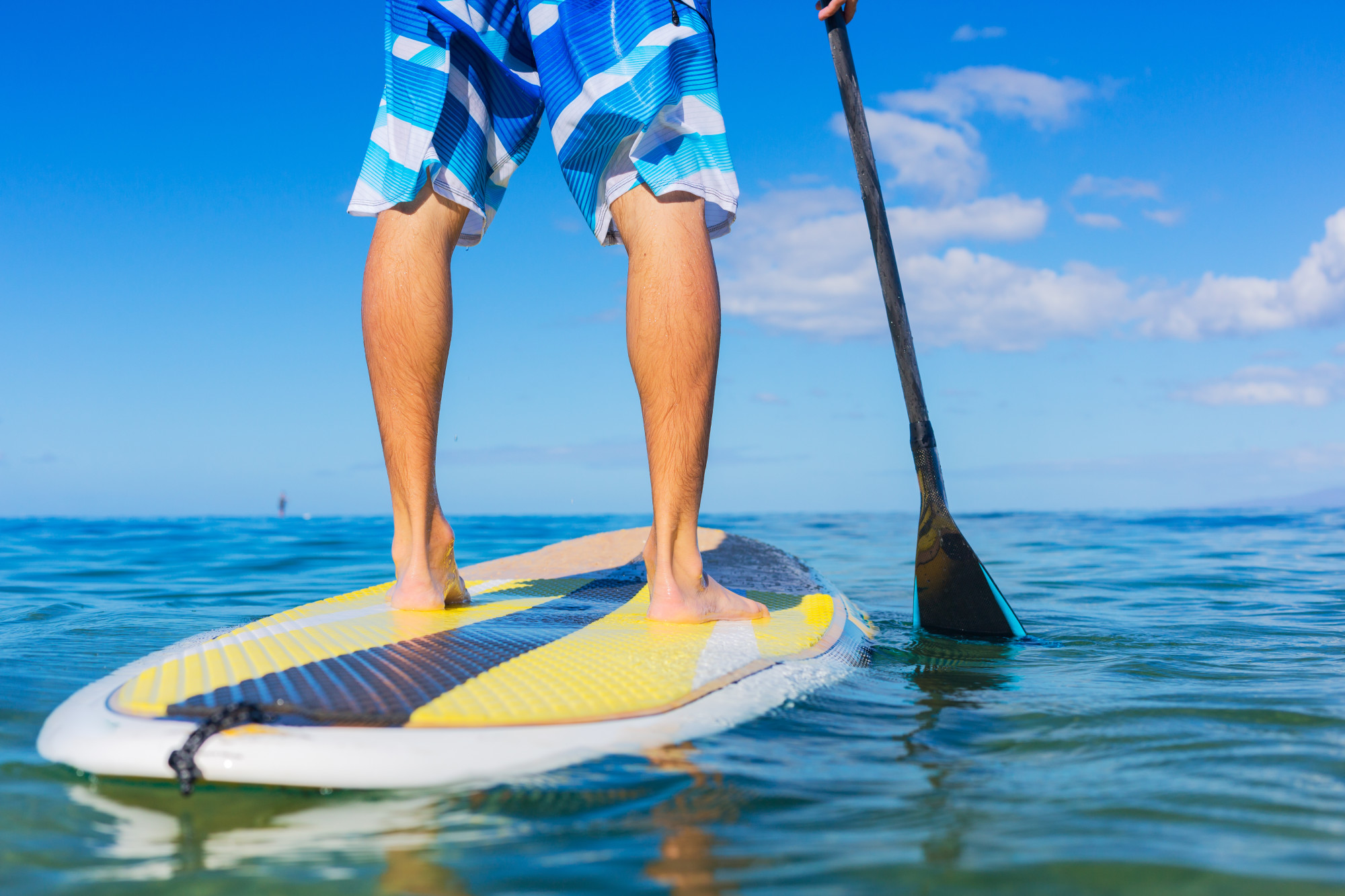 Paddle boarding tips - Man standing on paddle board with only waist down visible